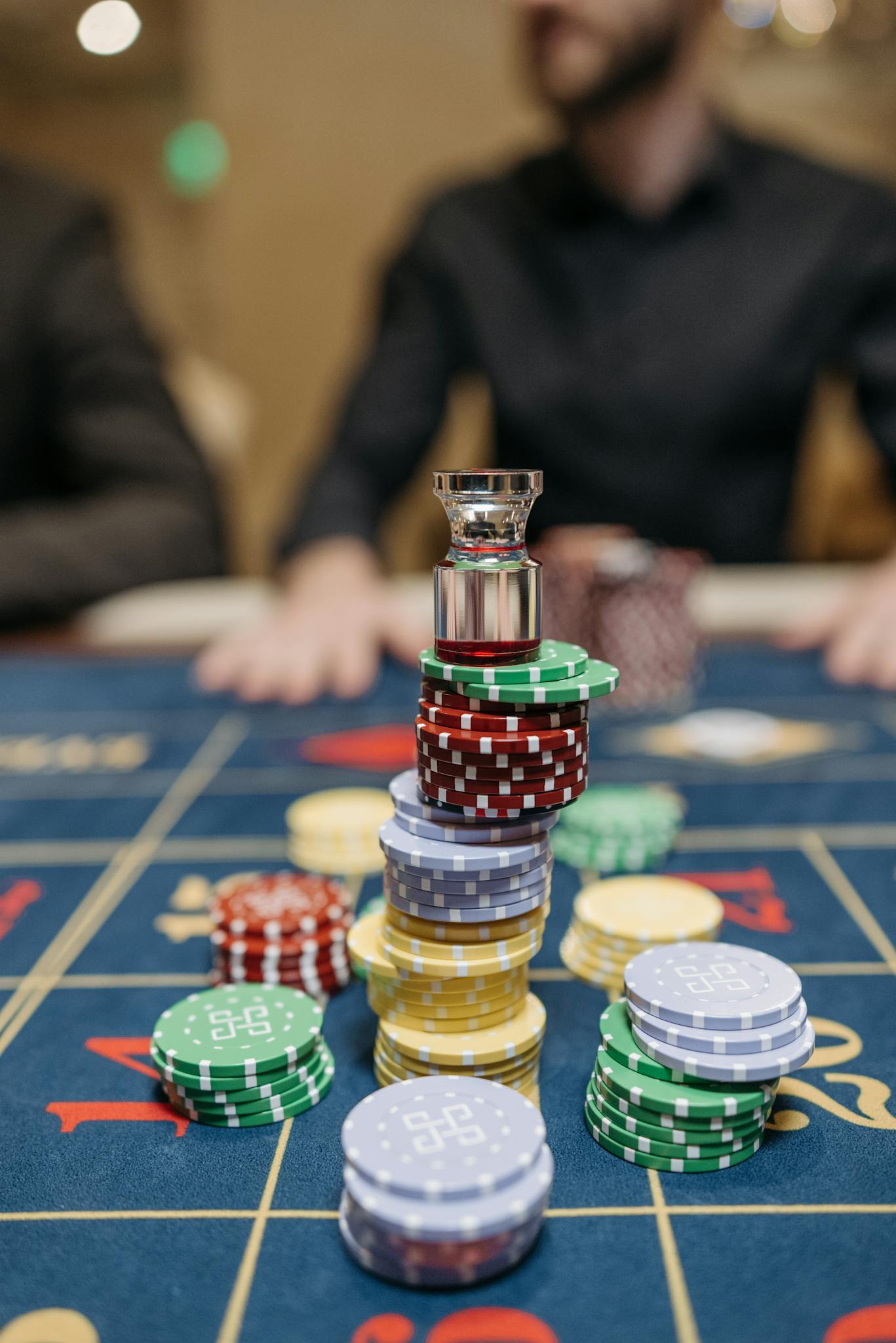 Close-up of colorful casino chips stacked on a roulette table in a casino setting.